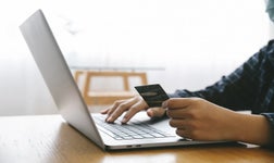 Man Holding credit card and using a laptop while shopping online