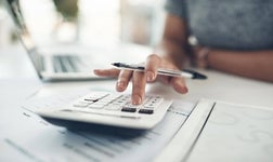 Close-up of a female professional using a calculator and financial documents.