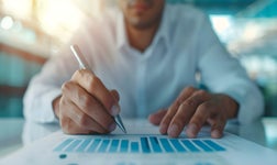 A person in an office annotates a piece of paper displaying a graph.