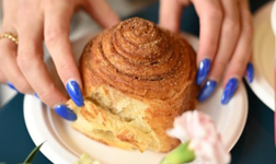 baker with blue nails holding a pastry