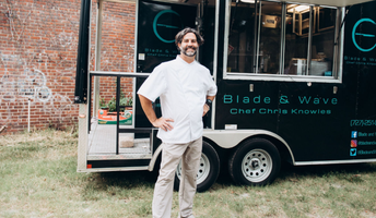 Chef stands smiling in front of food truck