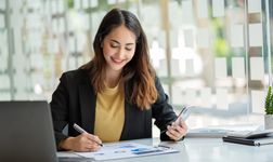 Young woman doing bookkeeping on her laptop and mobile phone app