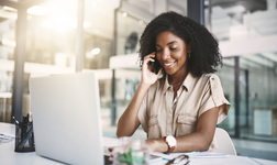 Woman on the phone in front of laptop in an office