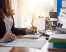 Business woman at working with financial reports and laptop computer in the office.