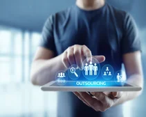 Man on iPad with 'outsourcing' feature hovering above screen