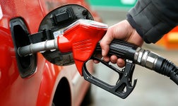 personal filling up vehicle with gas at fuel station