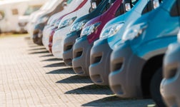 Variety of Vans Lined up in a Parking Lot During Sunny Weather
