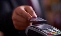 person putting a card on a POS terminal to pay