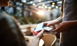 Close-up of unrecognizable woman using modern gadget while making online payment in cafe, nfc technology concept